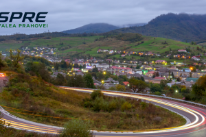 Drum șerpuitor și panorama unei localități de pe Valea Prahovei la lăsarea serii.